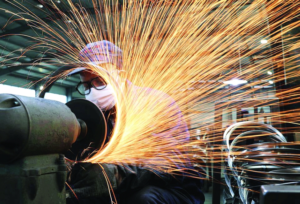 A worker wearing a face mask works on a production line manufacturing bicycle steel rim at a factor in Hangzhou, Zhejiang province, China. — Reuters