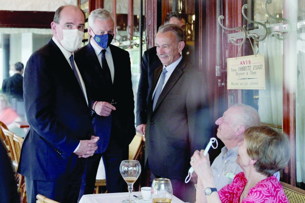 French Prime Minister Jean Castex (L) meet people as they leave the Brasserie Lipp restaurant after a lunch as France reopens indoor restaurant dining and a relaxation of a curfew, the third phase in a four-stage lifting of virus restrictions, in Paris on Wednesday.  — AFP