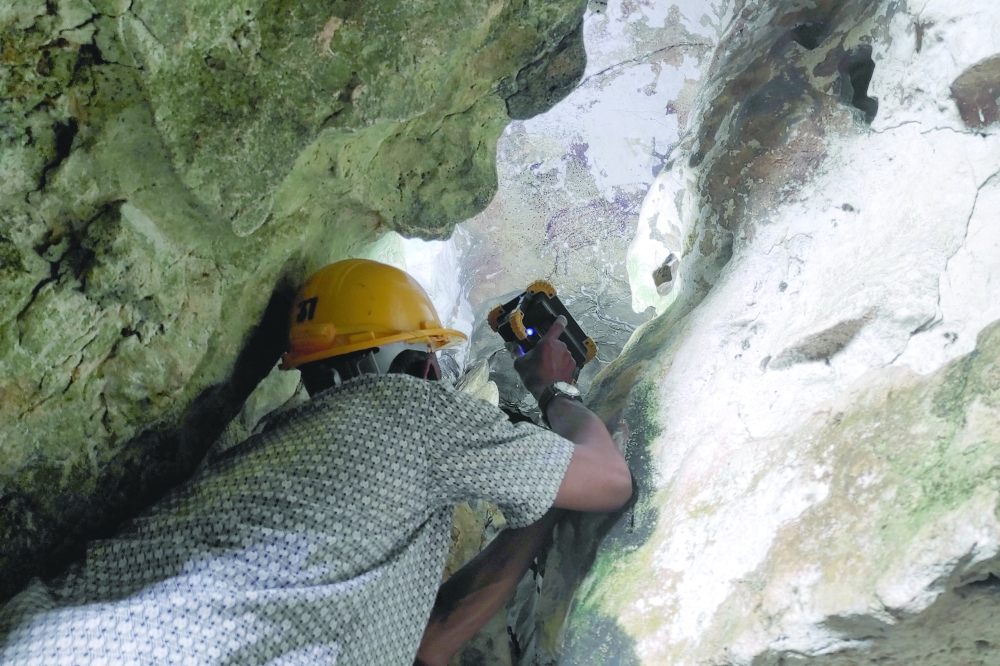 Archeologists inspect world's oldest limestone cave painting decaying due to climate change, in Maros. — Reuters