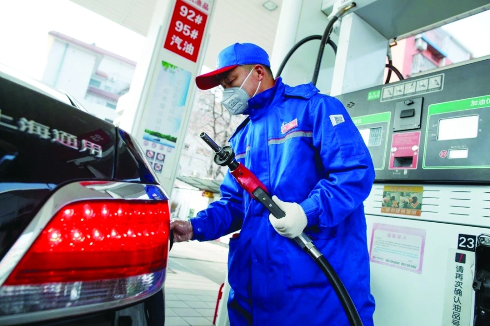A pump attendant refuels a car at a gas station in Beijing.