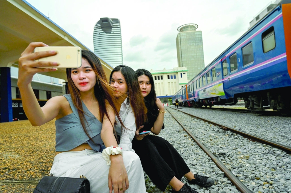 Women posing for a selfie next to a train at a railway station in Phnom Penh. - AFP