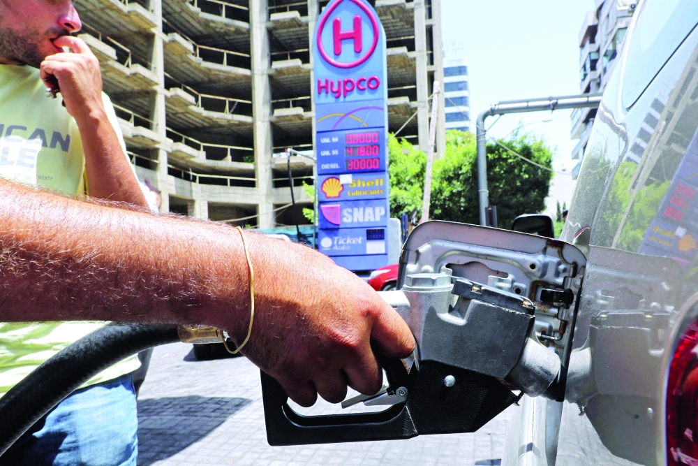 An employee fills a car with gasoline at a petrol station in Beirut amidst severe fuel shortages.- AFP