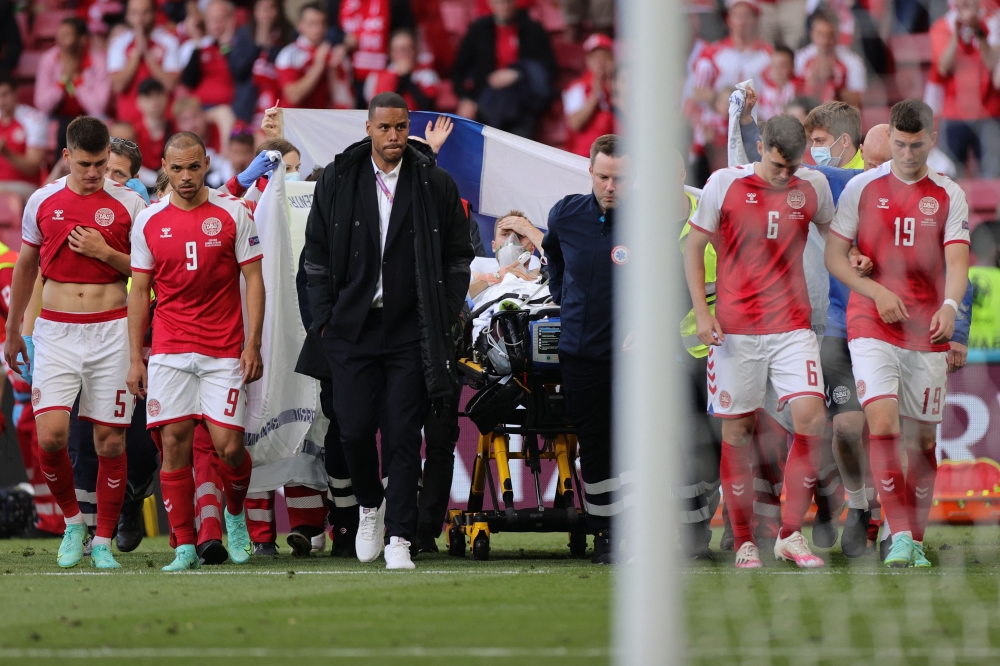 Denmark's players escort Denmark's midfielder Christian Eriksen (C) as he is evacuated after collapsing on the pitch during the UEFA EURO 2020 Group B football match between Denmark and Finland at the Parken Stadium in Copenhagen on June 12, 2021. 