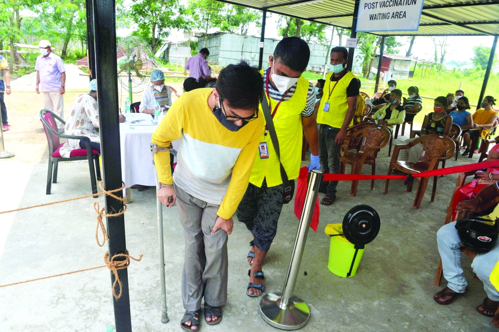 Unique Foundation volunteers assist a physically challenged man during a vaccination drive against the coronavirus at Medica North Bengal cancer hospital some 15 Km from Siliguri. - AFP 