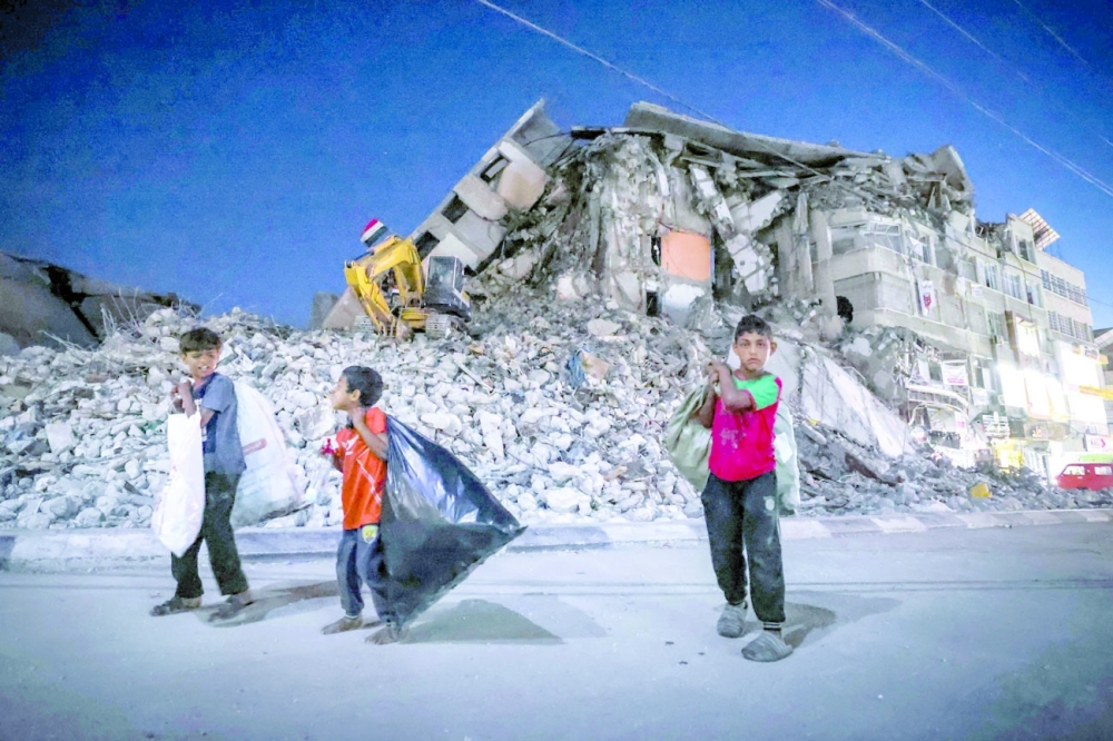 Palestinian boys walk past the destroyed Al Shuruq tower in Gaza City's Al Rimal neighbourhood during the recent confrontations between Hamas and Israel. - AFP File Photo 