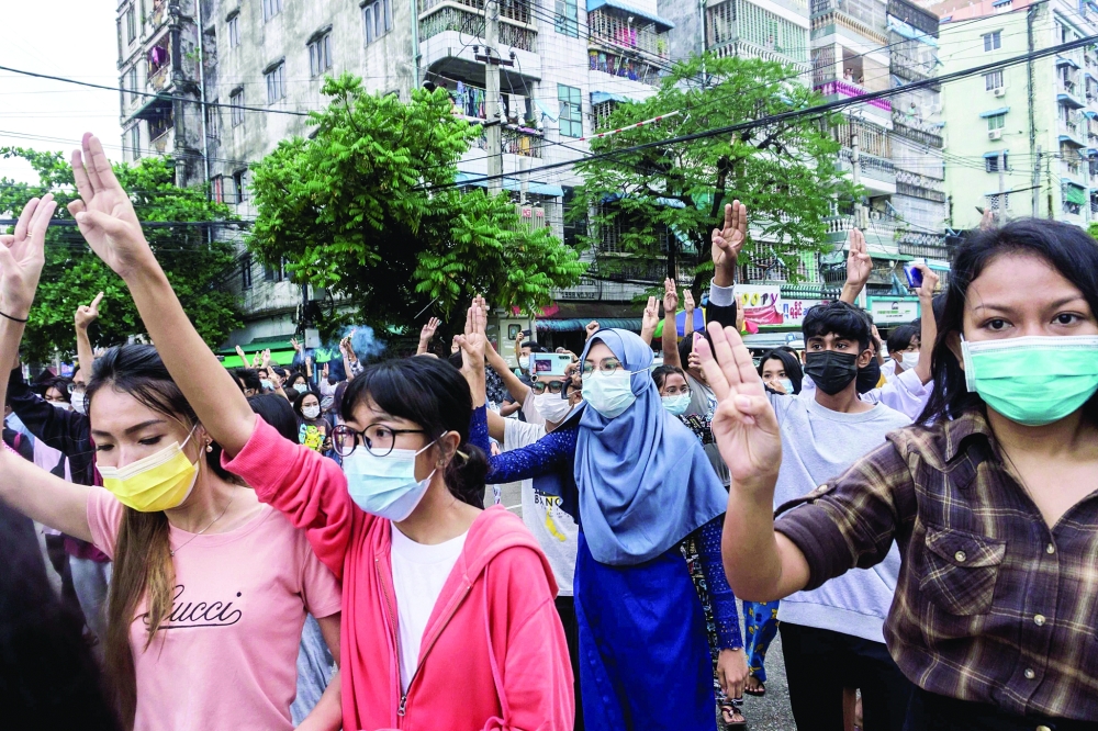 Protesters make the three-finger salute as they take part in a flash mob demonstration in Yangon. - AFP 