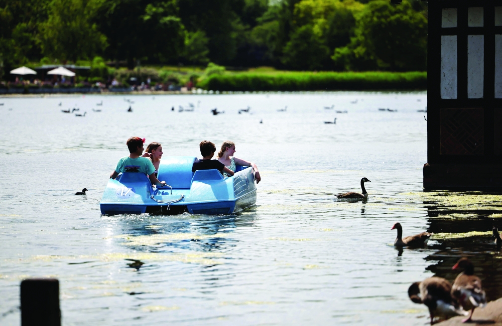 People ride in a pedalo in the sunshine in Hyde Park in London. - AFP 