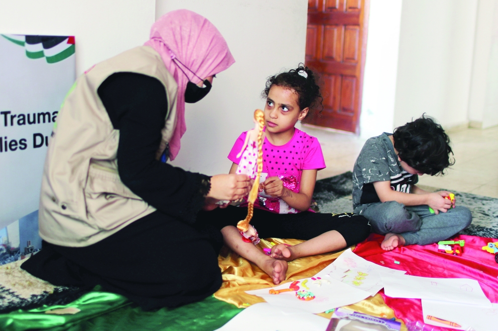 A psychologist plays with Palestinian girl Suzy Eshkuntana, who was pulled out from the rubble of her house, as part of a mental health support session in Gaza City. - Reuters File Photo 
