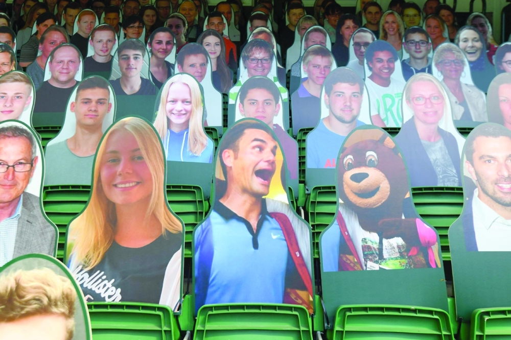 A look-alike silhouette of Roger Federer (C) is seen among others replacing the public among empty seats ahead of the start of the ATP Championships tournament in Halle, western Germany. -- AFP