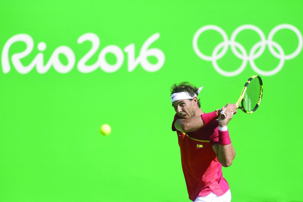 (FILES) In this file photograph taken on August 14, 2016, Spain's Rafael Nadal returns the ball to Japan's Kei Nishikori during their men's singles bronze medal tennis match at the Olympic Tennis Centre of the Rio 2016 Olympic Games in Rio de Janeiro. Rafael Nadal said June 17, 2021, that he was withdrawing from Wimbledon and the Tokyo Olympics "after listening to my body". / AFP / JAVIER SORIANO


