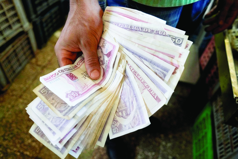 A vendor shows Cuban pesos notes in a public market in Havana. - Reuters 