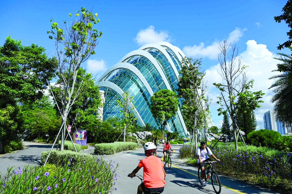 People cycling along a path next to the Flower Dome in the Gardens by the Bay in Singapore. - AFP