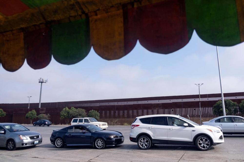 People queue in cars near the US-Mexico border as they wait for a vaccination center to open in Tijuana, Baja California state, Mexico on June 17, 2021.  