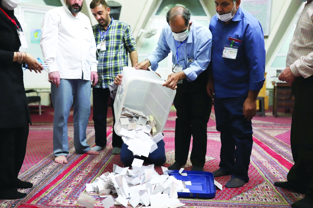 An electoral staff empties full ballot boxes after voting ended in the presidential election in Tehran. — Reuters