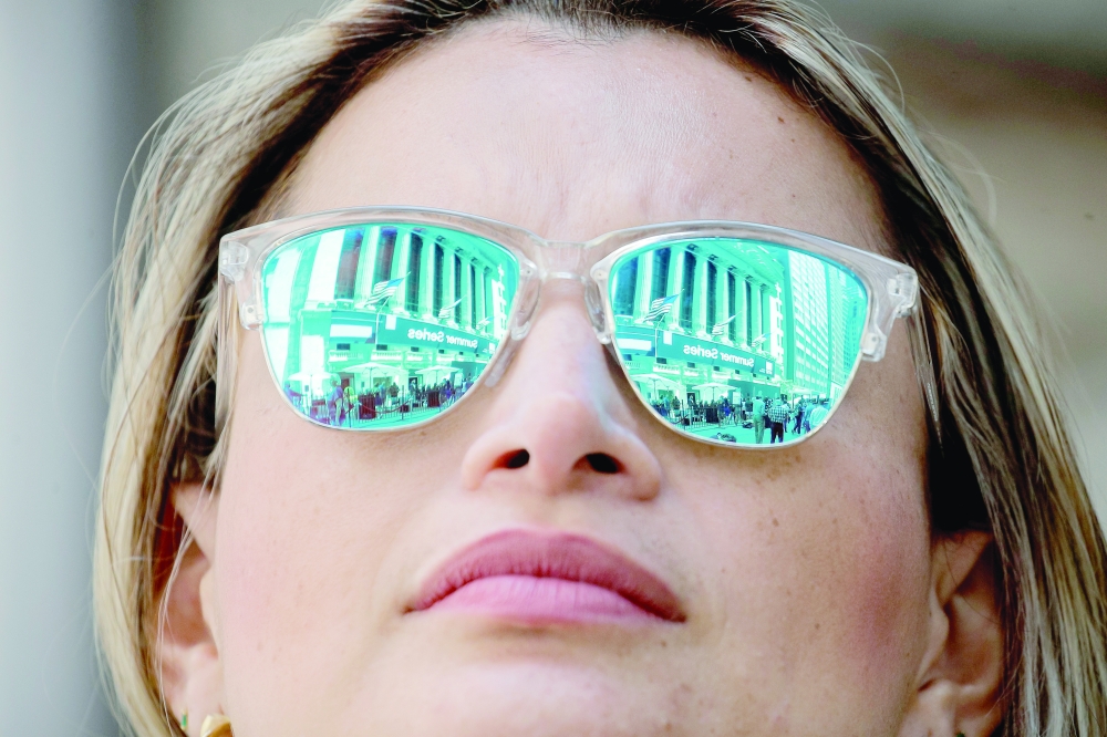 The New York Stock Exchange (NYSE) is reflected in a woman's glasses in New York City. - Reuters