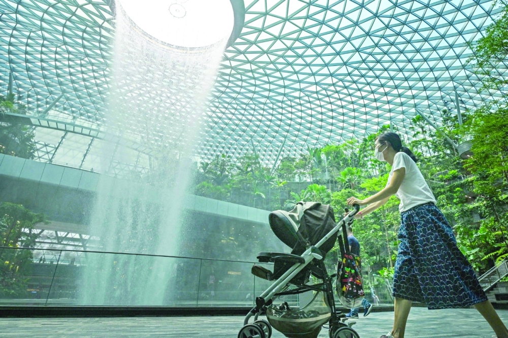A woman pushes a baby stroller past the rain vortex at Jewel Changi Airport in Singapore on Thursday. — AFP  
