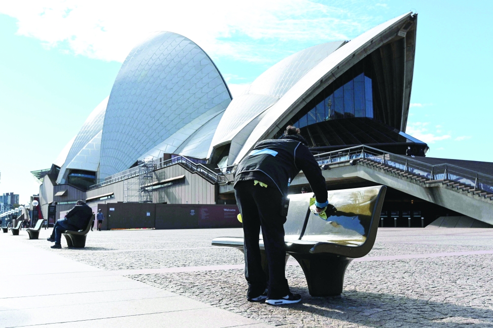 A worker cleans public seating outside the Opera House in Sydney after authorities locked down several central areas of Australia's largest city to contain an outbreak of the highly contagious Delta variant. - AFP 