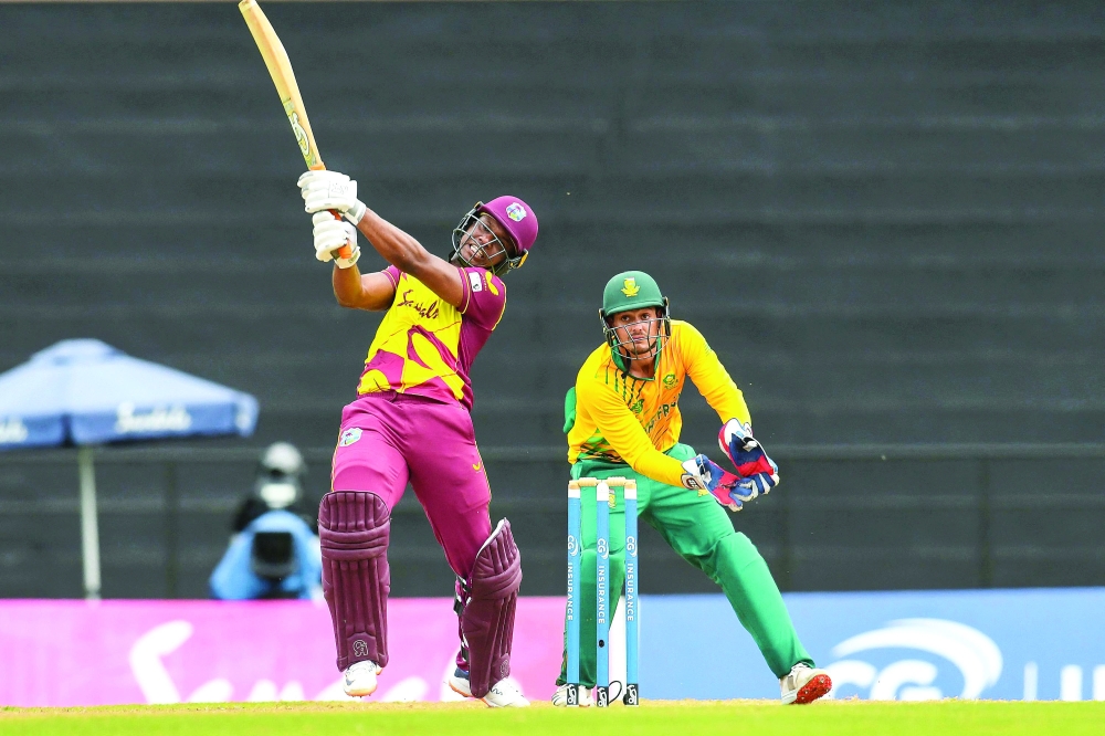 Evin Lewis (L) of West Indies hits 6 and Quinton de Kock (R) of South Africa watch during the 1st T20I between West Indies and South Africa at Grenada National Cricket Stadium, Saint George's, Grenada, on June 26, 2021. / AFP / Randy Brooks

