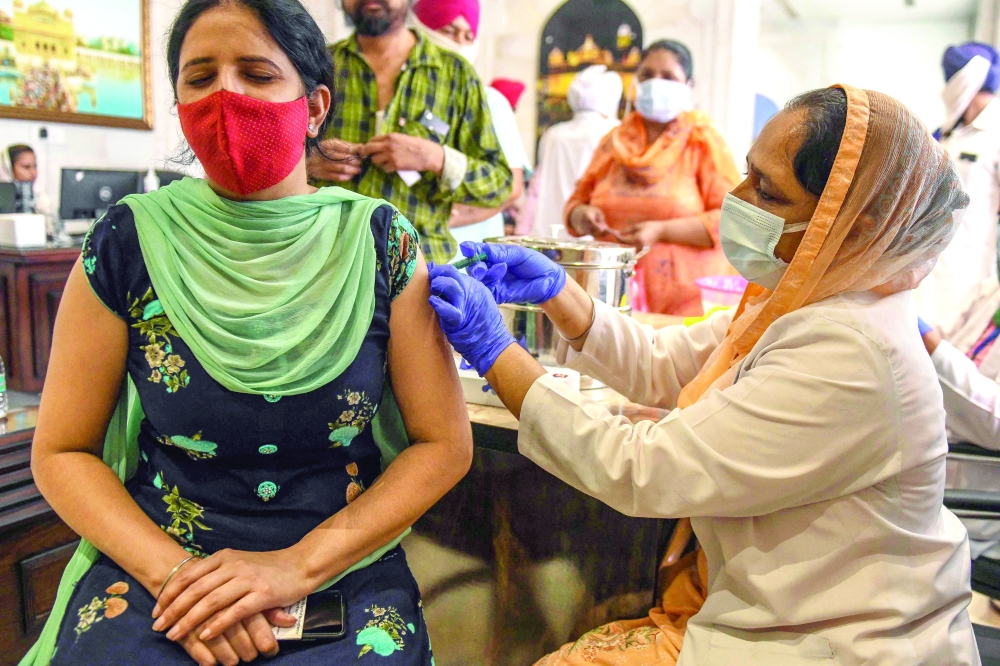 A health worker inoculates a woman with a dose of the Covaxin vaccine against Covid-19 inside the premises of the Golden Temple in Amritsar on Tuesday. — AFP