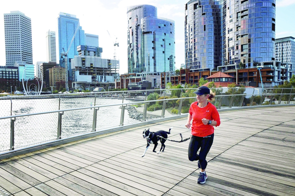 A woman runs with her dog through Elizabeth Quay in Perth on Tuesday as several positive Covid-19 cases have led to a four-day lockdown of the Perth metropolitan area. — AFP