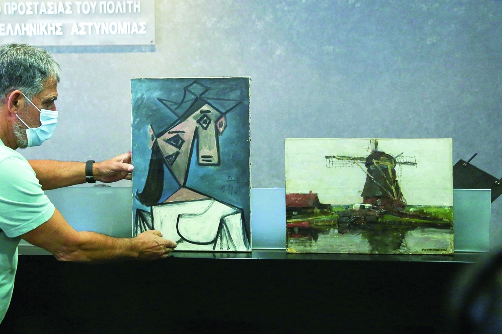 The paintings “Woman’s Head” by Pablo Picasso and “Mill” by Piet Mondrian, both stolen from Greece’s National Gallery in 2012, are displayed during a presentation to members of the media at the Ministry of Citizens Protection in Athens on Tuesday. — Reuters