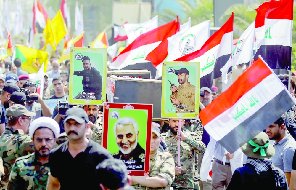 Members of Iraqi Popular Mobilisation Forces (PMF) attend a symbolic funeral of fellow members of PMF who were killed by US air strikes on the Syria-Iraq border, in Baghdad, on Tuesday. — Reuters