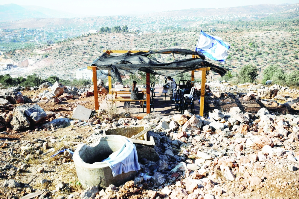 Jewish settlers sit together in Givat Eviatar, a new Israeli settler outpost, near the Palestinian village of Beita in the Israeli-occupied West Bank on June 23. - Reuters