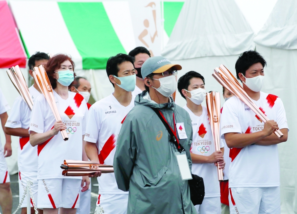 Torch relay runners attend a torch kiss event after their relay on a public road was cancelled in Sammu, Chiba Prefecture, Japan. -- Reuters