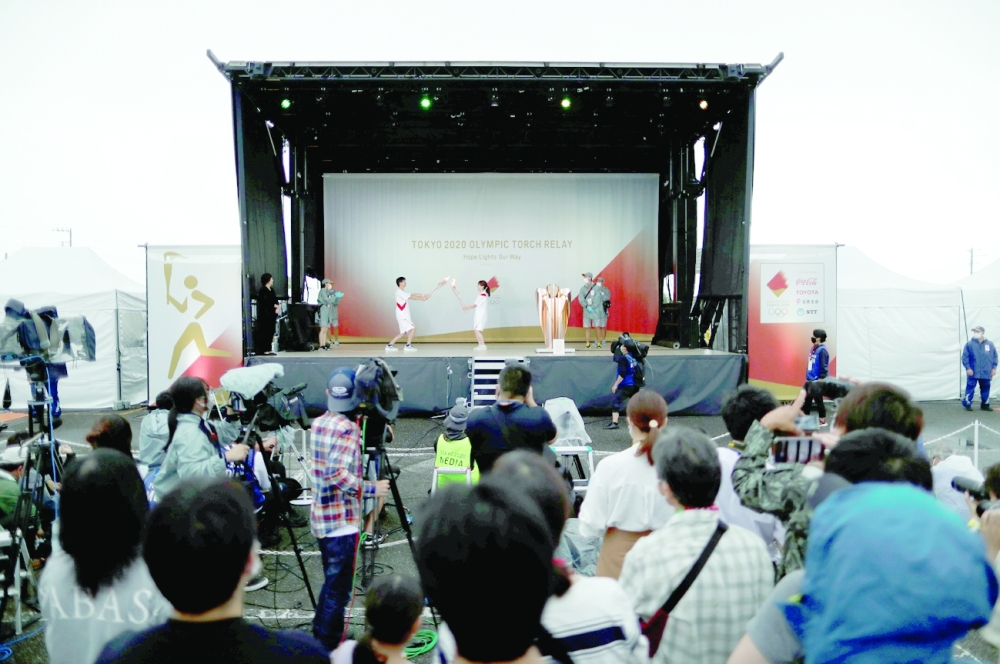 Torch relay runners attend a torch kiss event after their relay on a public road was cancelled in Sammu, Chiba Prefecture, Japan. -- Reuters