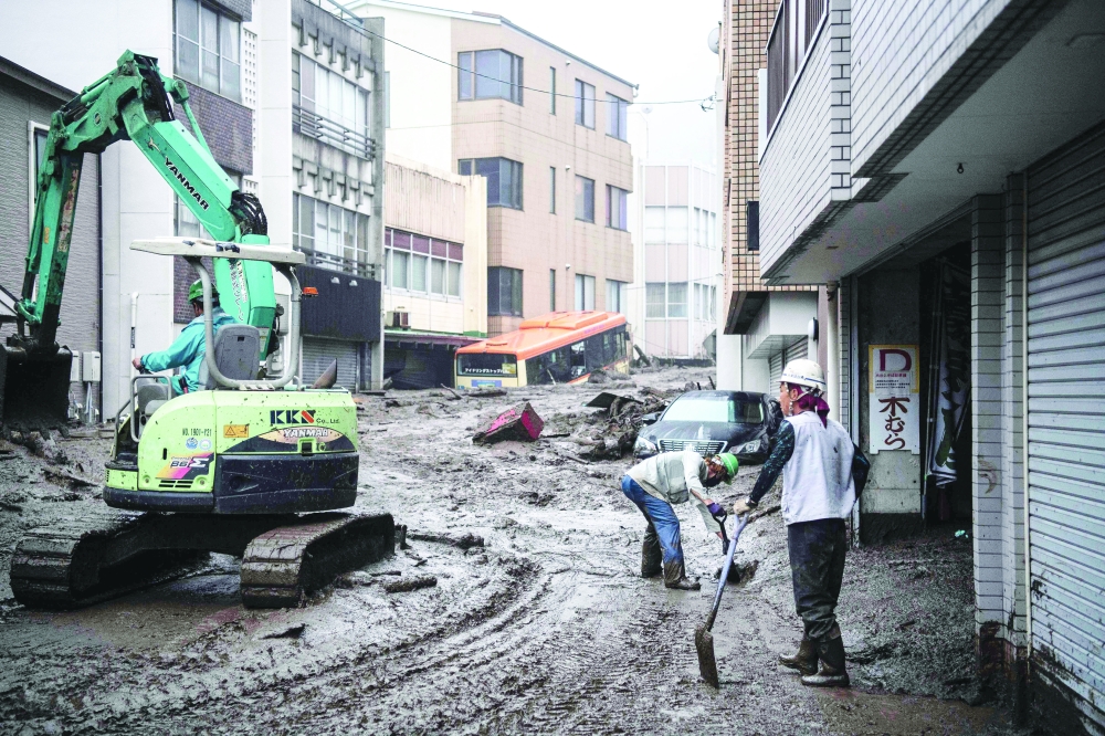 Workers remove mud and debris at the scene of a landslide following days of heavy rain in Atami in Shizuoka Prefecture. - AFP