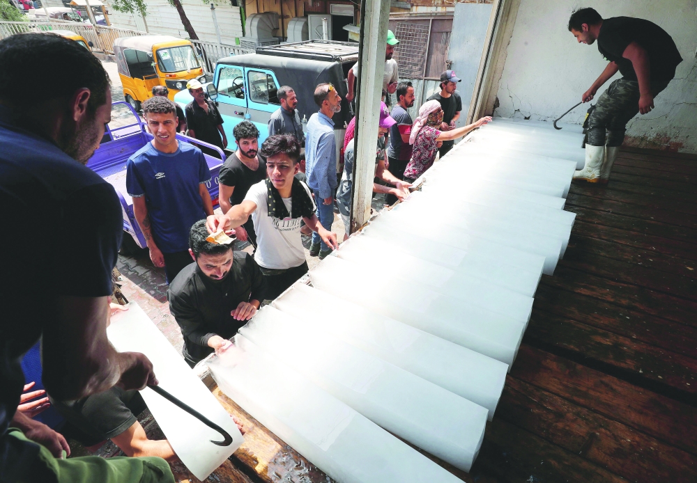 Iraqis buy ice blocks at a factory in Sadr City, east of the capital Baghdad amid power outages and soaring temperatures. - AFP