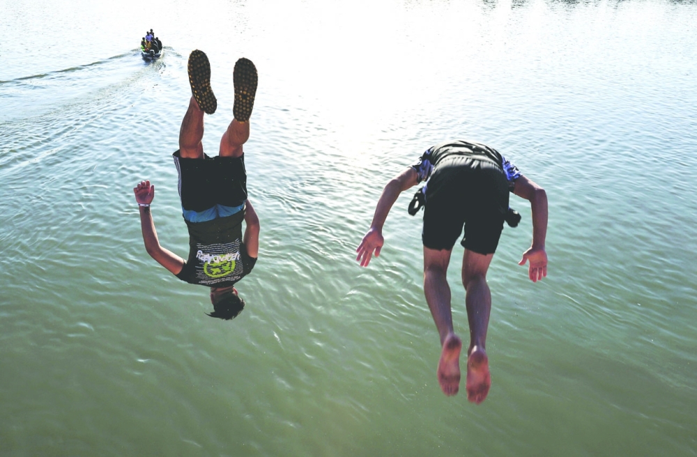 People dive into the Tigris river to cool down in the summer heat in Baghdad. - Reuters