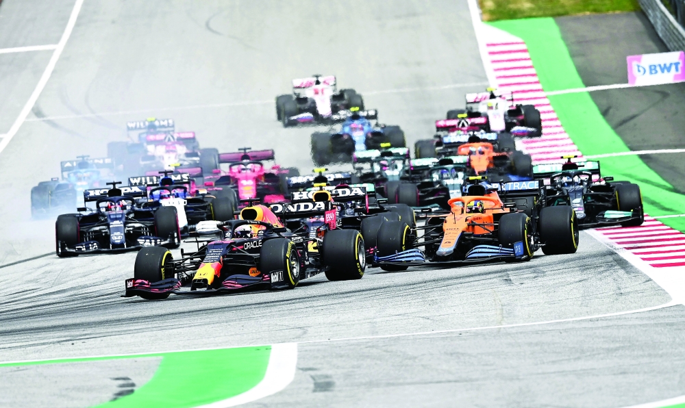 TOPSHOT - Red Bull's Dutch driver Max Verstappen (front) leads the pack as drivers take the start of the Formula One Austrian Grand Prix at the Red Bull Ring race track in Spielberg, Austria, on July 4, 2021. / AFP / Joe Klamar

