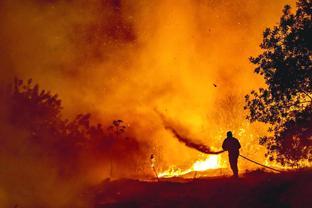 A firefighter battles the flame in a forest on the slopes of the Throodos mountain chain, as a giant fire rages on the Mediterranean island of Cyprus, on Saturday. -- AFP 