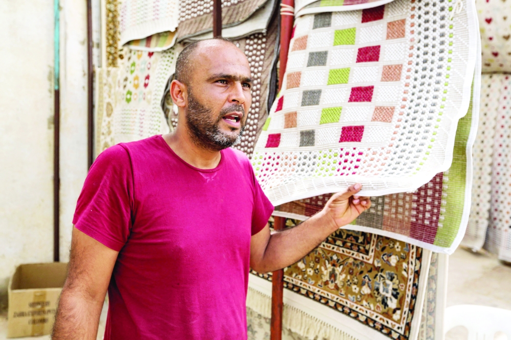 A merchant stands next to displayed carpets in a shop at the Maghreb souk of Tunisia's southern town of Ben Guerdane. - AFP