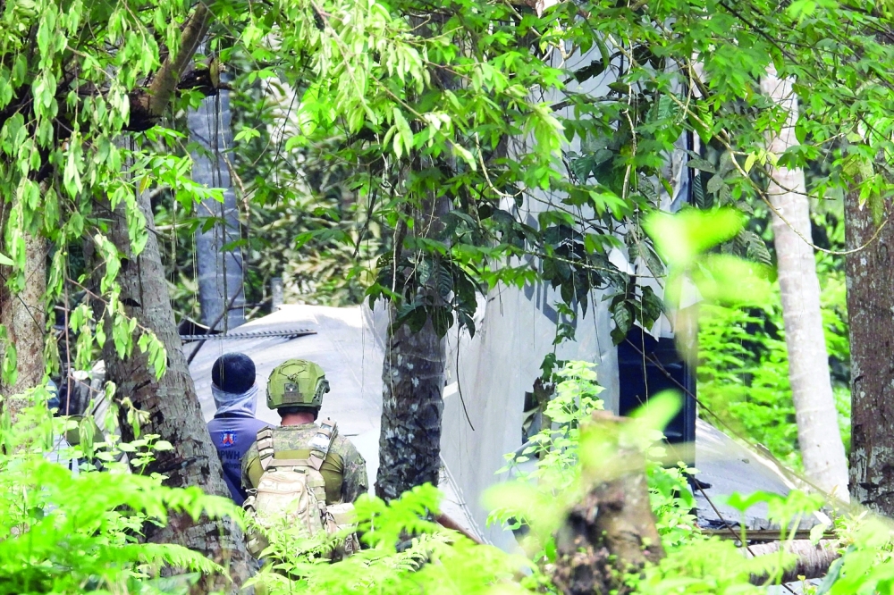 Soldiers stand near wreckage of a Philippine Air Force C-130 transport aircraft, which crashed and killed 50 people after it overshot the runway, in Jolo town, Sulu province. - AFP