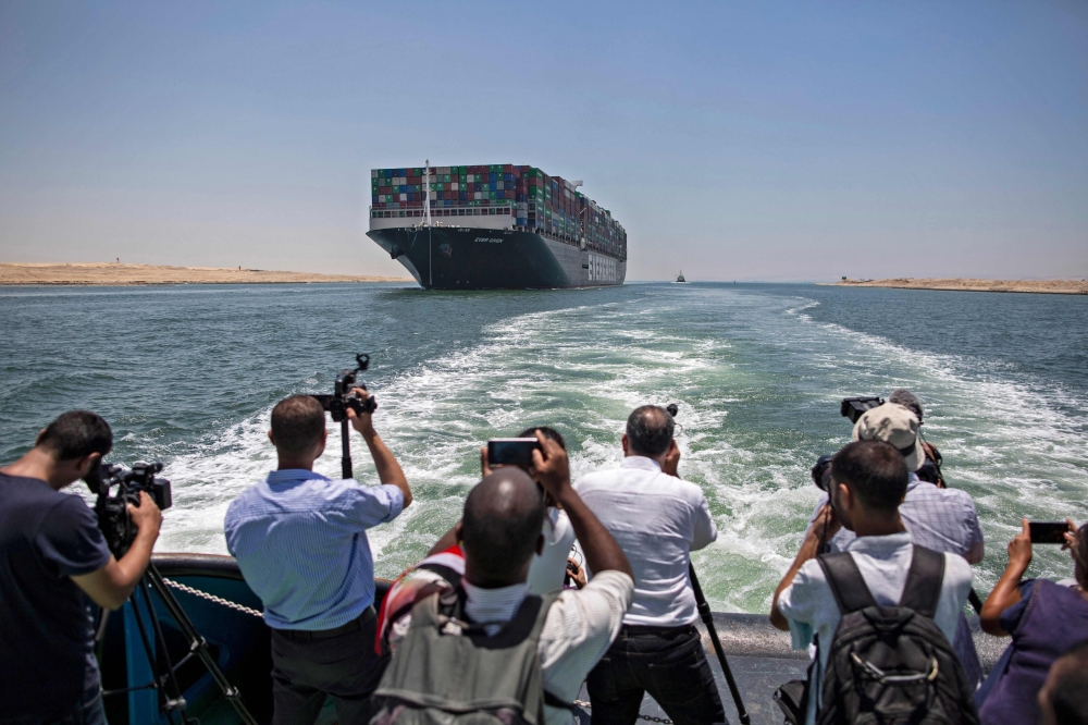 Journalists on a nearby boat film the Panama-flagged MV 'Ever Given' container ship sailing along Suez Canal on Tuesday. - AFP 