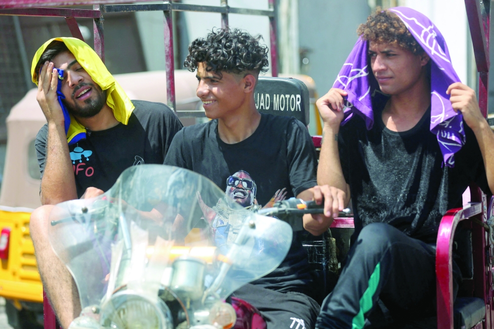 Iraqi youth react in the heat as they wait to buy ice blocks at a factory in Sadr City, east of Baghdad. - AFP