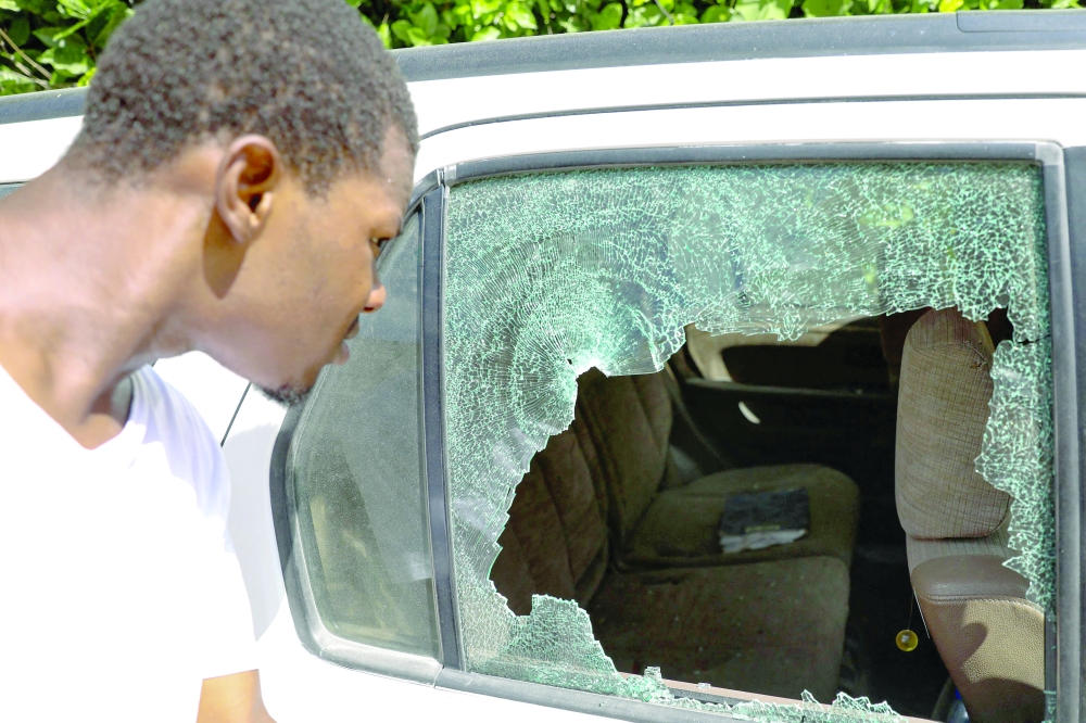 A man looks at the bullet holes in a car outside of the presidential residence in Port-au-Prince. -- AFP