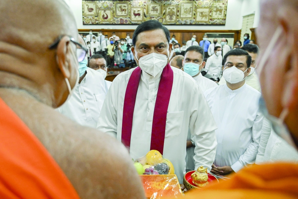 Basil Rajapaksa (C) receives blessing from Buddhist monks after signing documents during his swearing-in ceremony at the Ministry of Finance office in Colombo on Thursday. -- AFP

