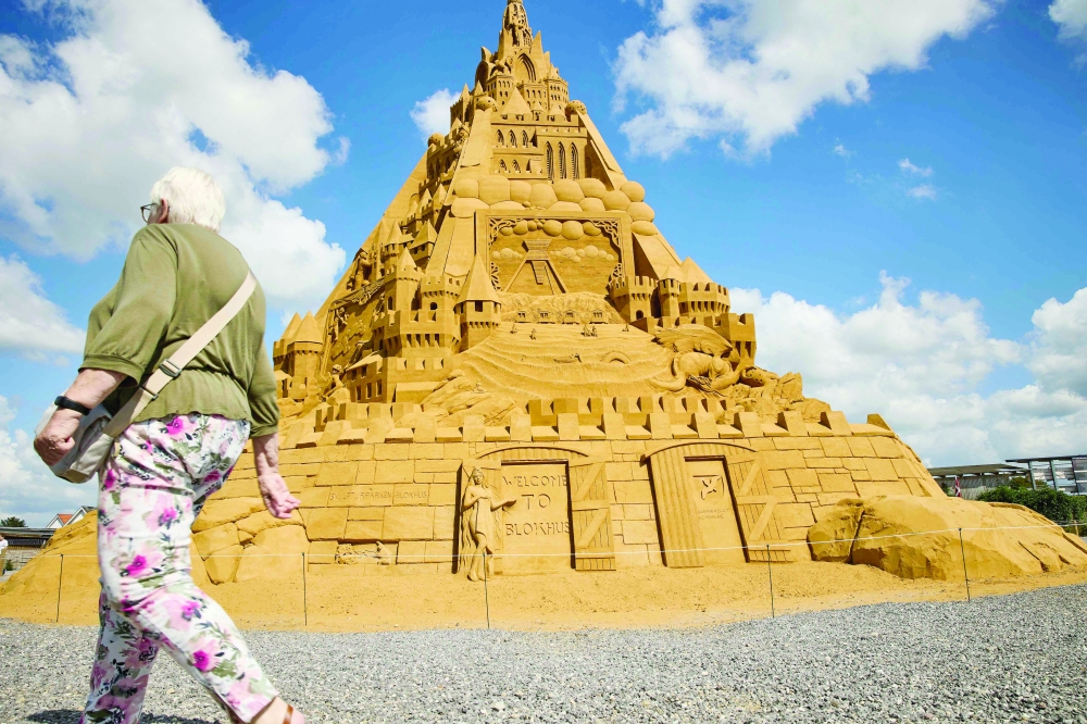 A woman walks past the world's tallest sand sculpture, under construction in Blokhus, Denmark. - AFP 