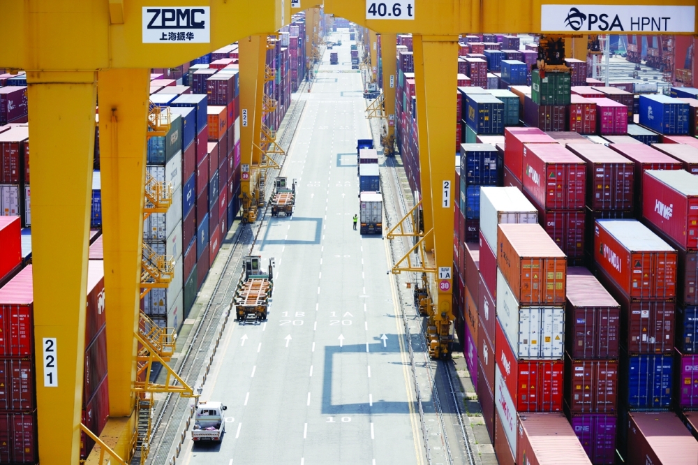 A truck driver stands next to his truck as he gets ready to transport a shipping container at Pusan Newport Terminal in Busan. - Reuters