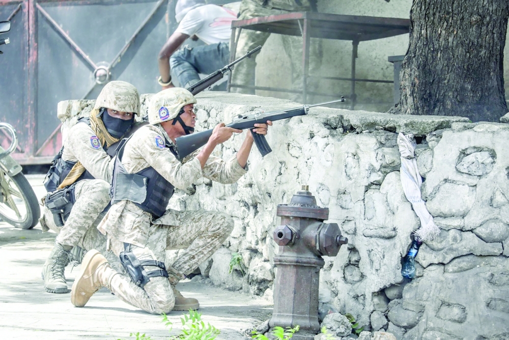 Security forces member exchange gunfire with armed men next to the Petionville police station in Port-au-Prince. - AFP