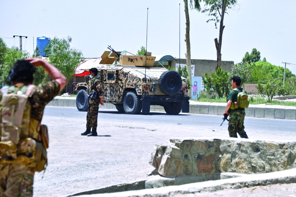 Afghan security personnel stand guard along the road amid ongoing fight between Afghan security forces and Taliban fighters in Kandahar. - AFP 