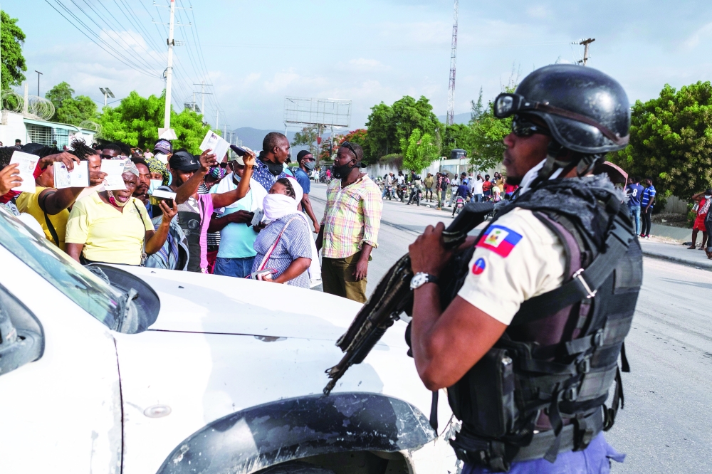 A Haitian National Policeman guard the entrance to the US Embassy as people gather to ask for asylum following the assassination of President Jovenel Moise, in Port-au-Prince, on Friday. - Reuters
