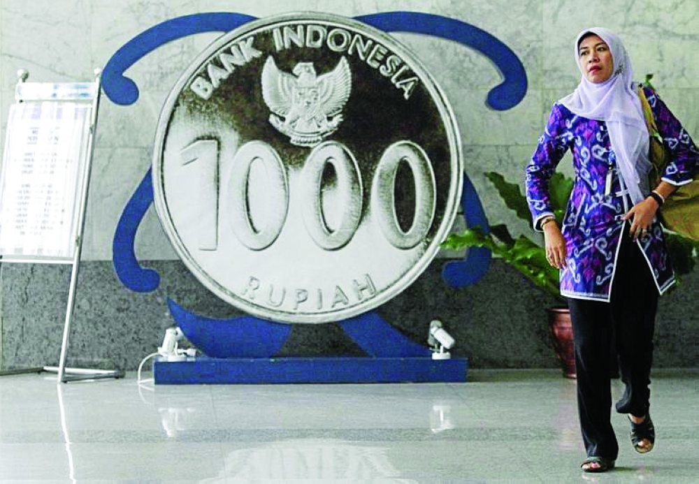 A woman walks past a poster of a one thousand rupiah coin inside Indonesia's central bank in Jakarta. — Reuters