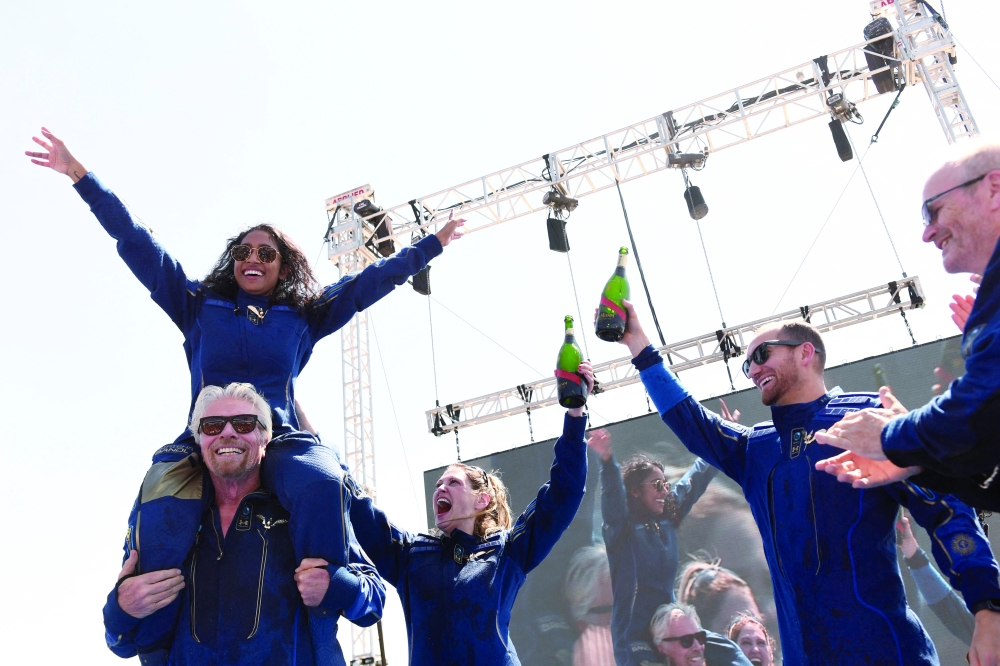 Virgin Galactic founder Sir Richard Branson(L), with Sirisha Bandla on his shoulders after flying into space aboard a Virgin Galactic vessel on Sunday. -- AFP