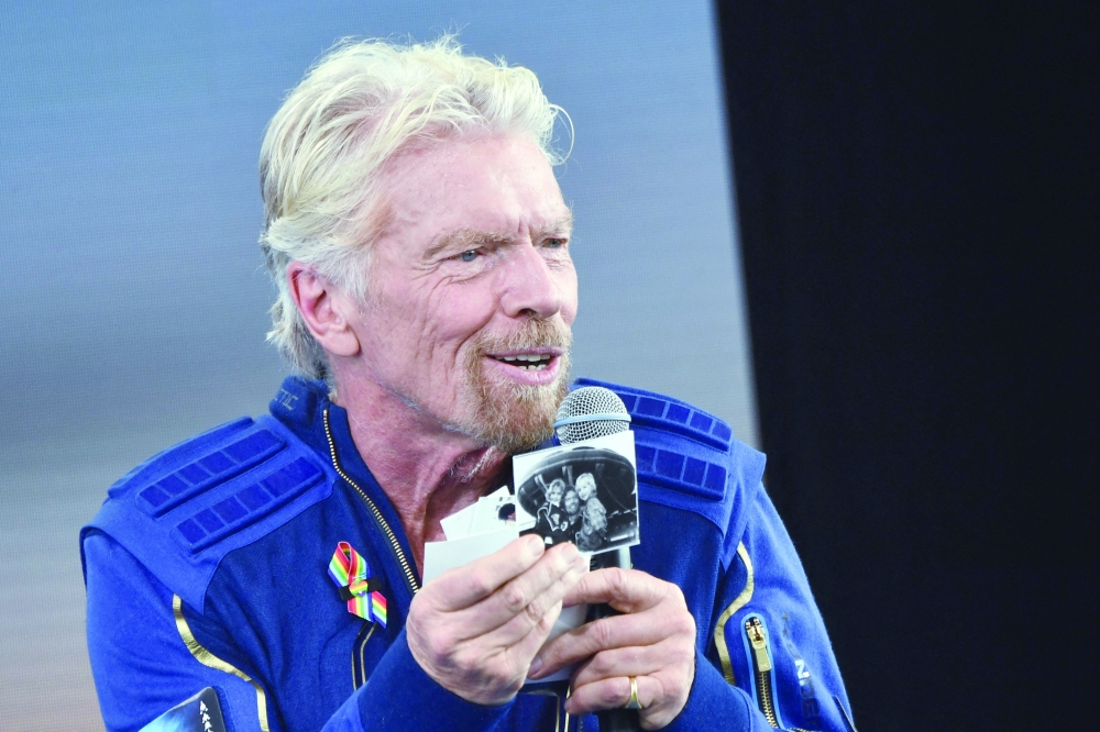 Sir Richard Branson holds up photos that he brought with him into space, as he speaks after flying into space aboard a Virgin Galactic vessel. -- AFP
