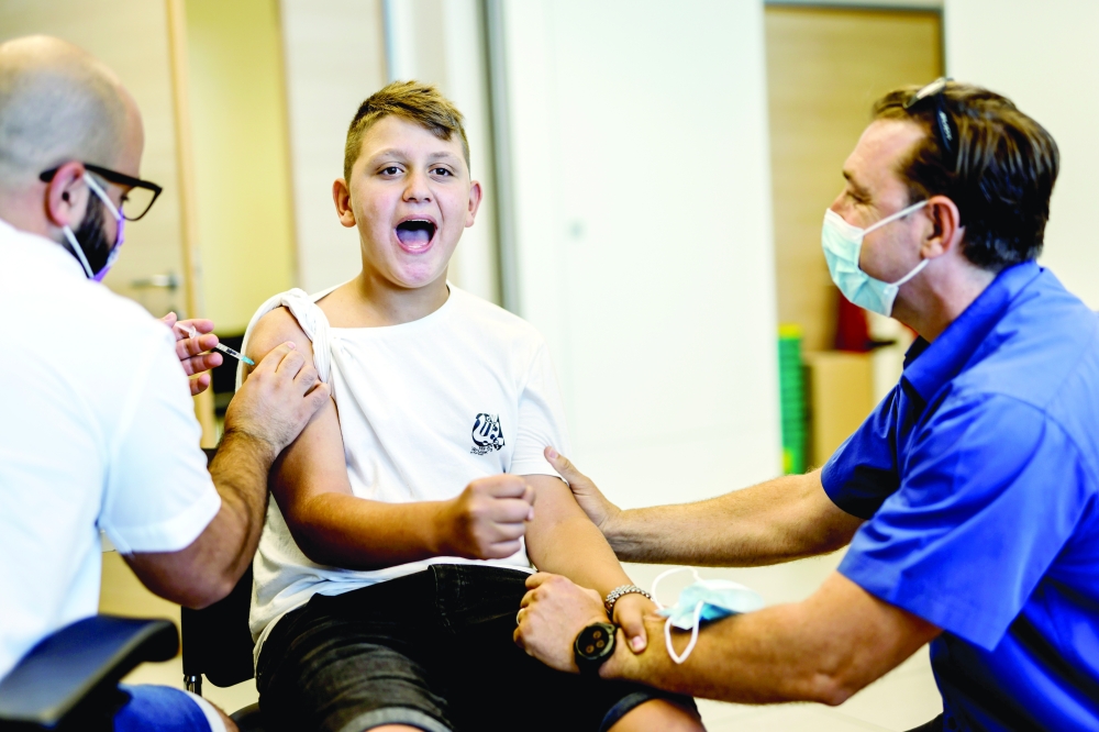A youth receives a vaccination against Covid after Israel approved the usage of the vaccine for youngsters aged 12-15, at a Clalit healthcare maintenance organisation in Ashkelon. - Reuters