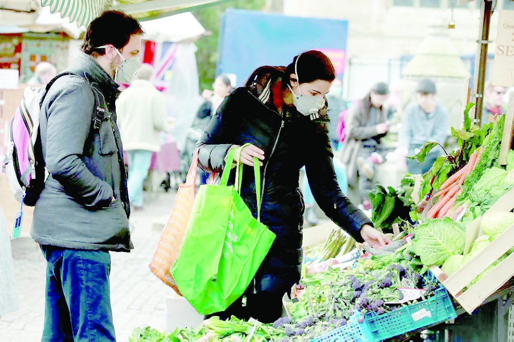 Shoppers wearing face masks at a market in Cambridge, Britain. — Reuters 